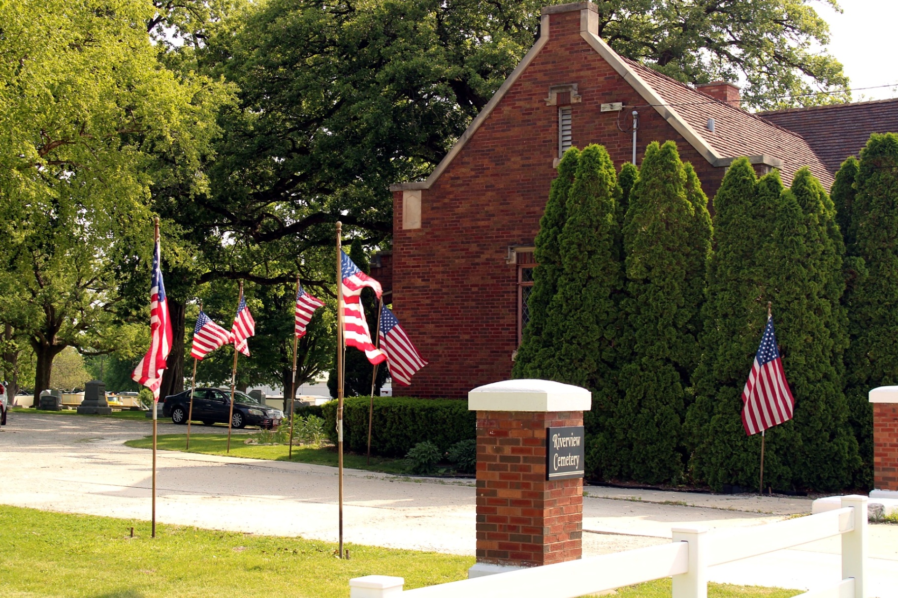 American flags lining the entrance to Riverview Cemetery near the brick chapel