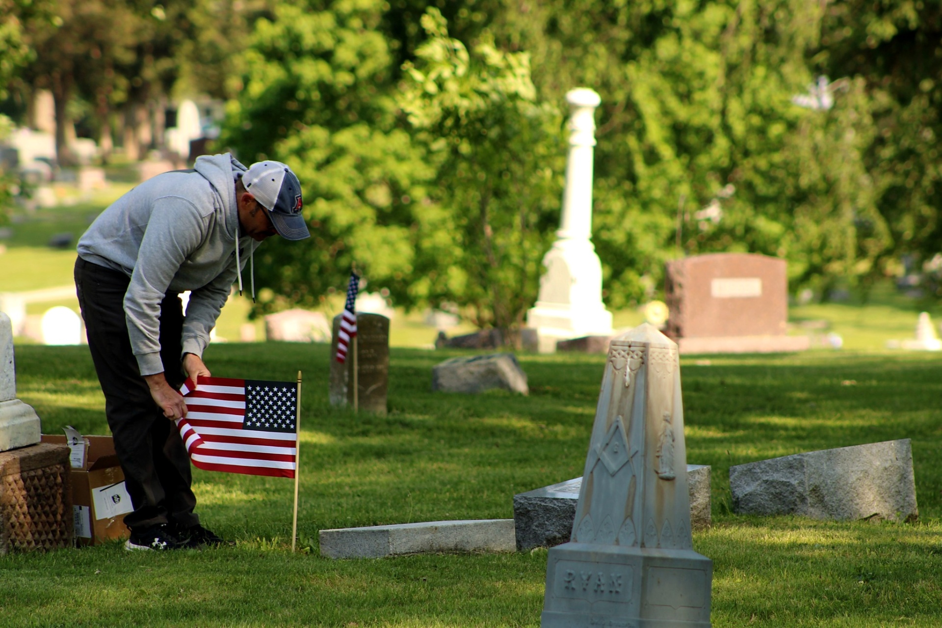 A volunteer placing an American flag at a historic grave marker