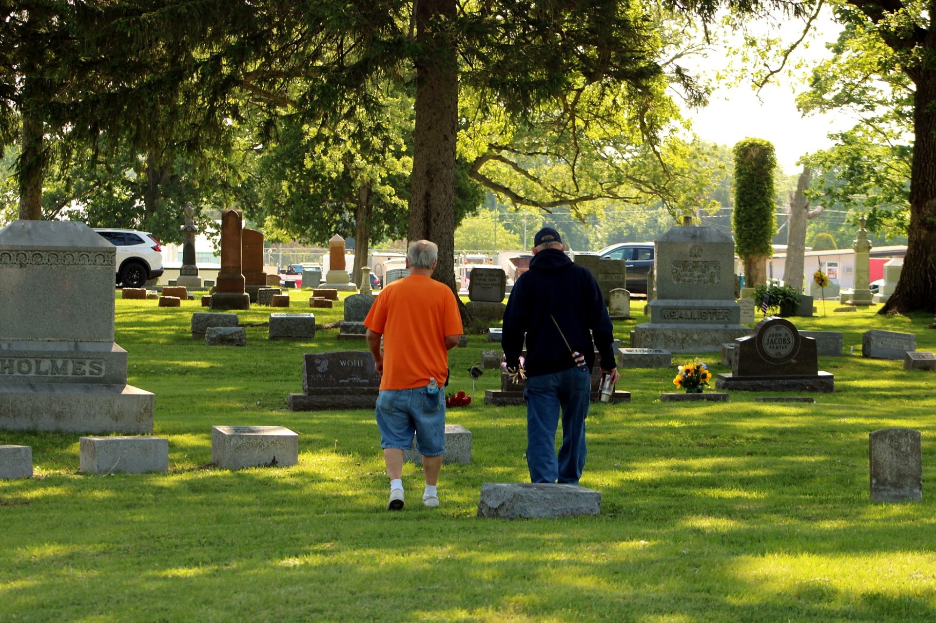 Two visitors walking through the cemetery on a sunlit Memorial Day morning