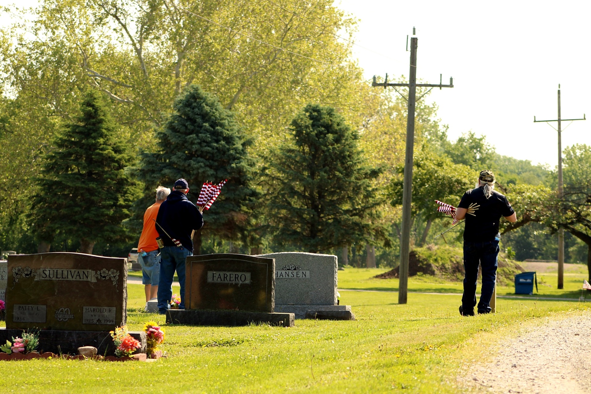 Volunteers carrying flags as they walk among the family monuments