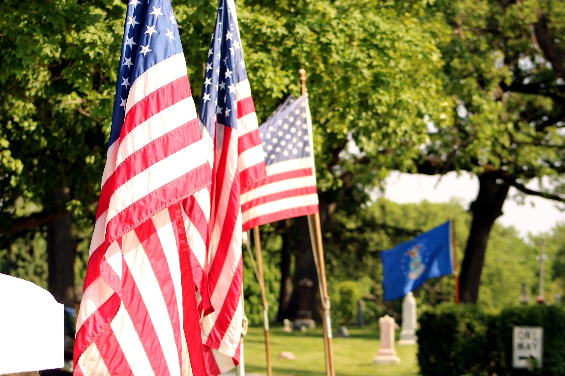 Ceremonial American flags and an Air Force flag displayed under the trees