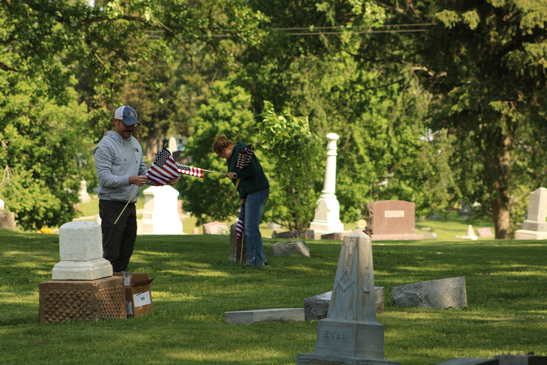 Volunteers placing American flags at veterans' graves on Memorial Day morning