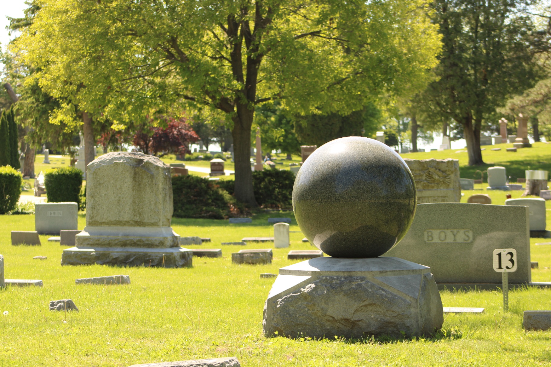 A polished granite sphere monument resting on a rough-hewn base in Section 13